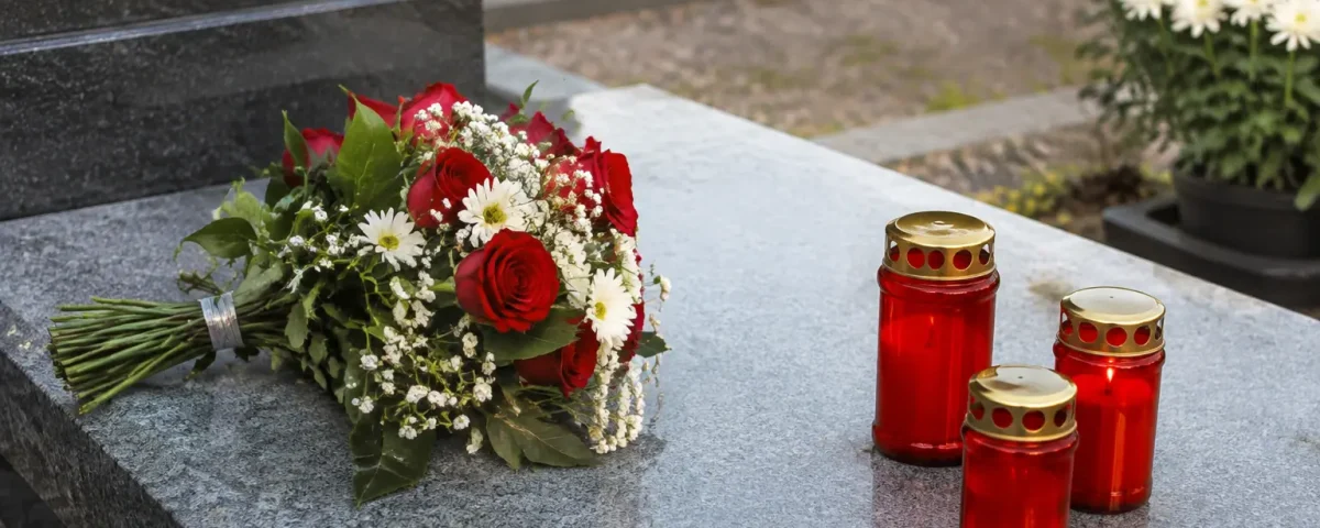 Pierre tombale grise avec bougies rouges et fleurs posees
