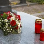 Pierre tombale grise avec bougies rouges et fleurs posees