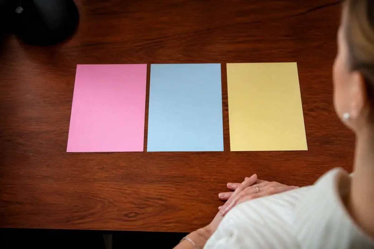 Trois fiches colorees alignees sur un bureau en bois